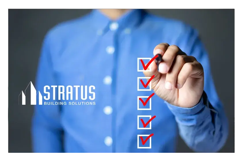 Person wearing a blue button down shirt checking off boxes in the foreground with a red marker. 